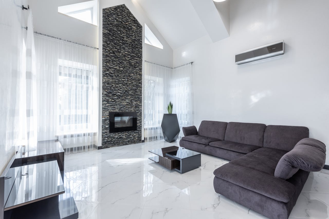 Elegant modern living room featuring a stone fireplace, sleek furniture, and airy ambiance.